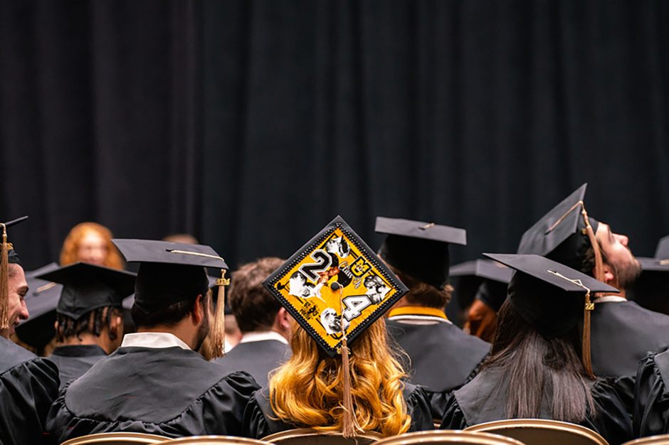 Person with decorated cap in crowd at commencement