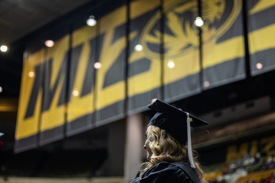 Graduate in front of Mizzou sign