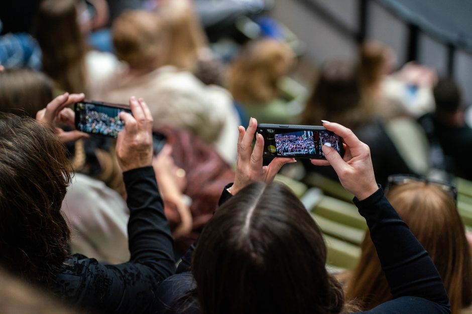 Hands hold phones taking photos