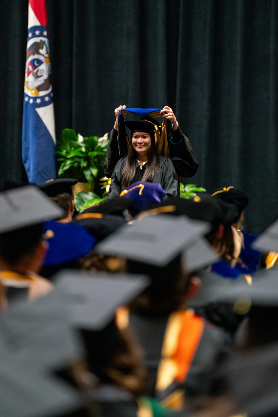 Person receives degree framed by others in mortar boards