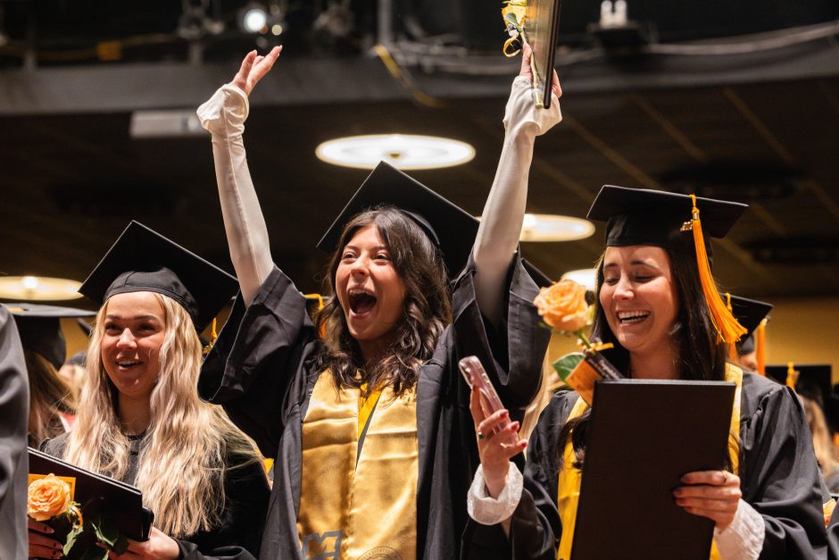 Graduate in crowd raises hands