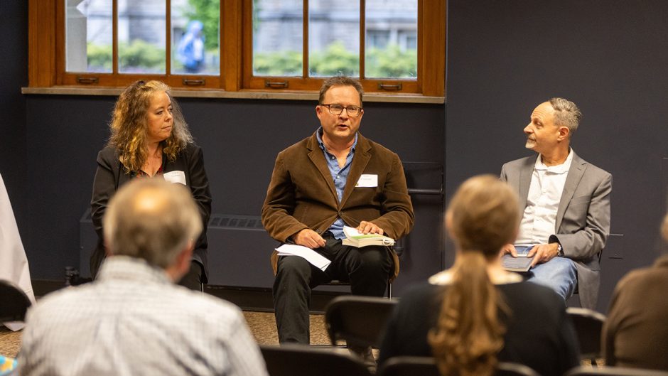 Man sitting with book speaks to audience