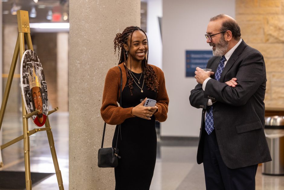 Two people talk in front of artwork