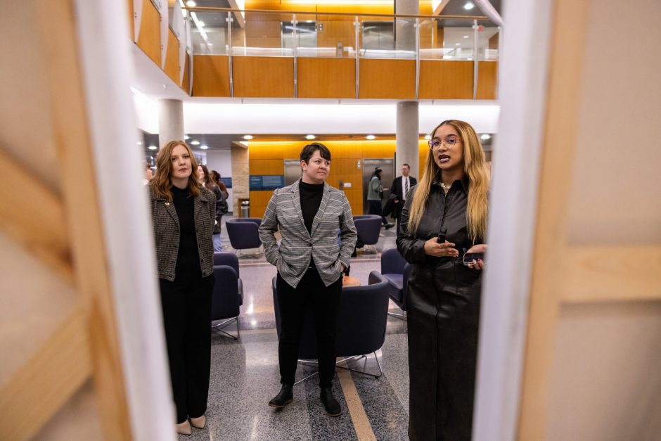 Three people look at artwork