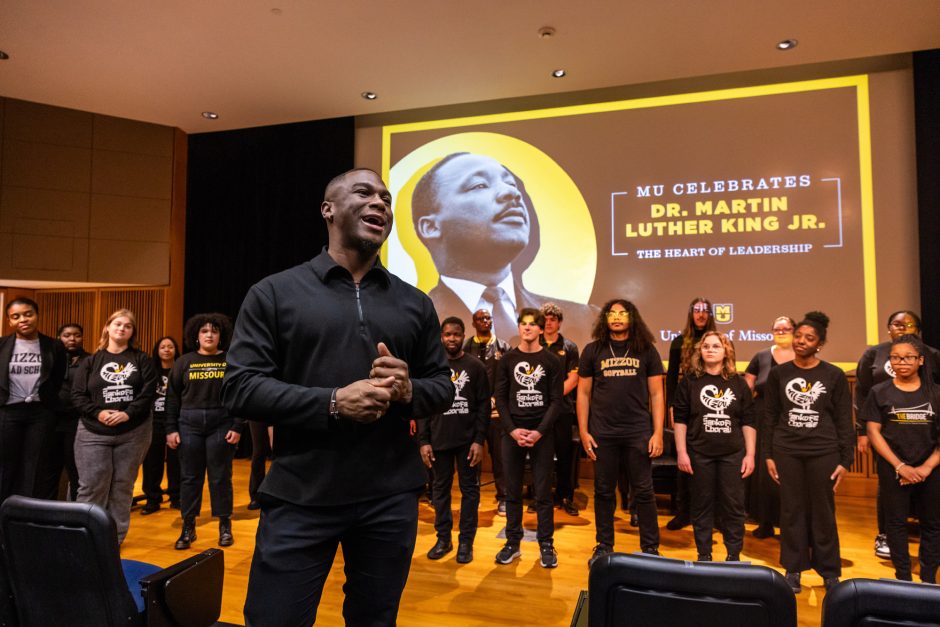 Man in front of choir with MLK graphic on screen in background