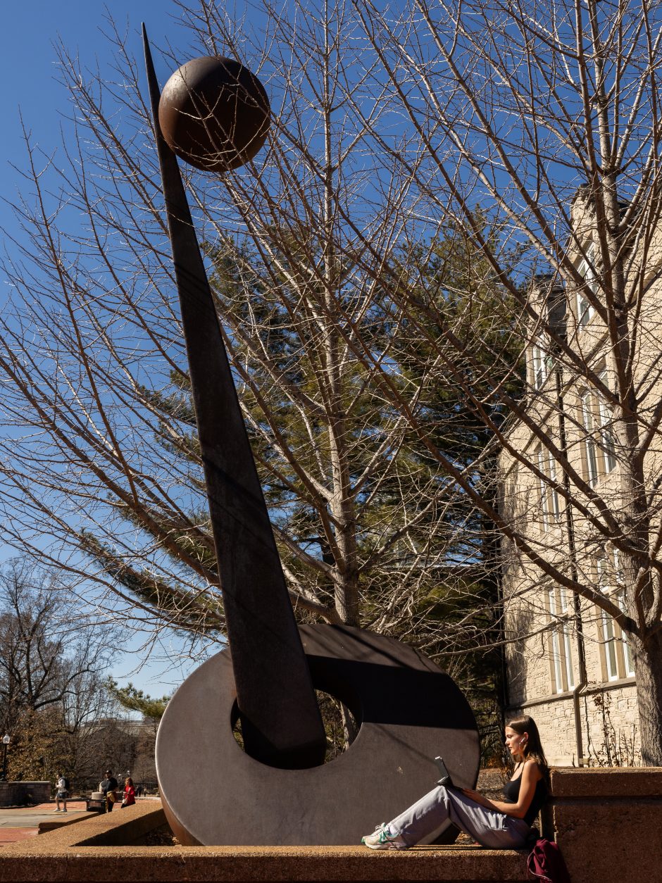 Student sitting near statue on campus