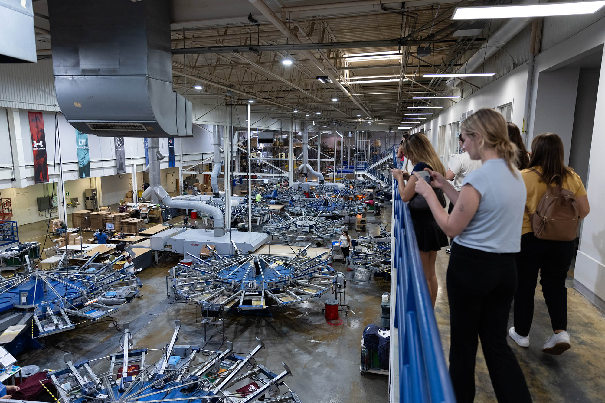 students looking at large machine in apparel factory