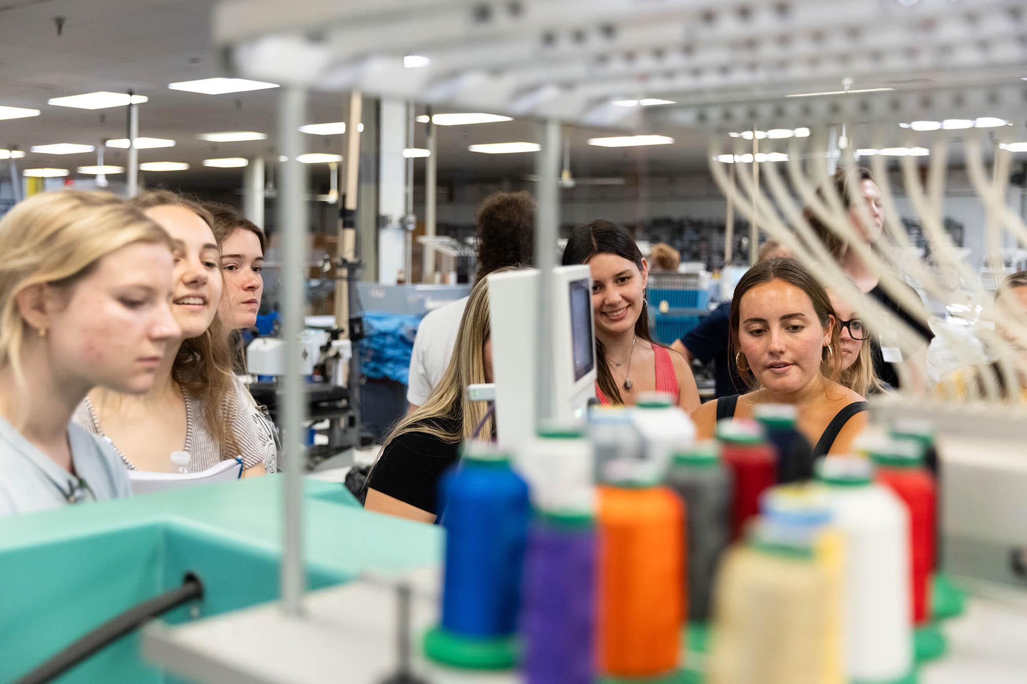 Students looking at large spools of thread.