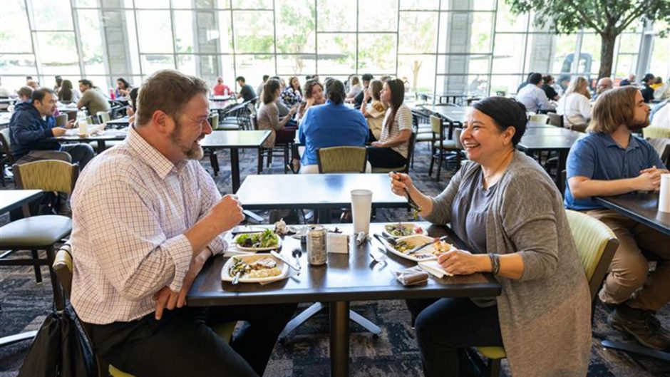 Two people eating lunch at a table in student center.
