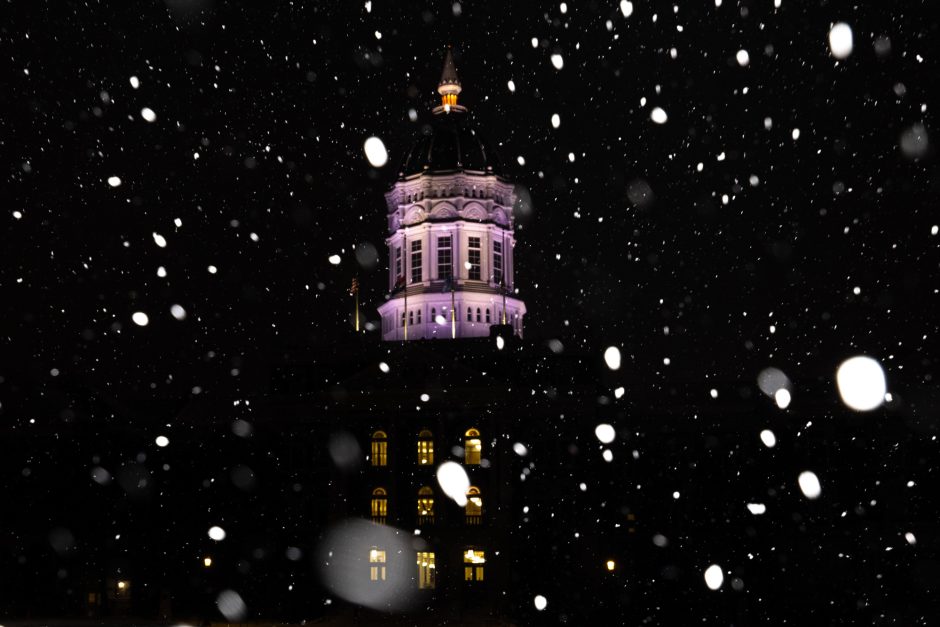 Jesse Hall illuminated at night as snow falls