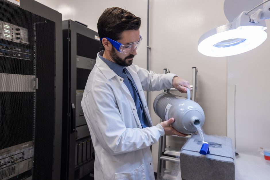 Researcher in lab coat pours liquid from a container