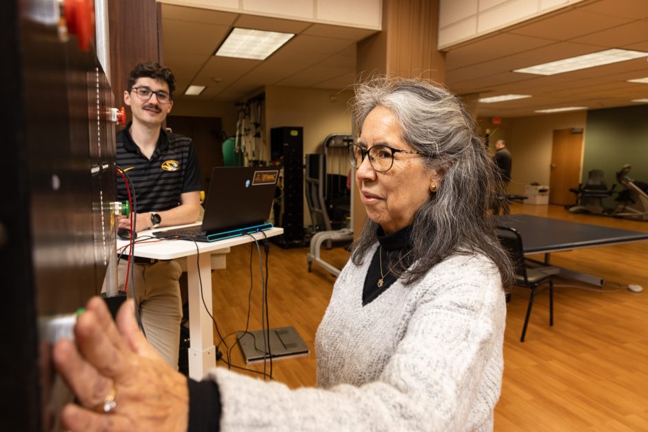 Person with arm extended as researcher looks on in background
