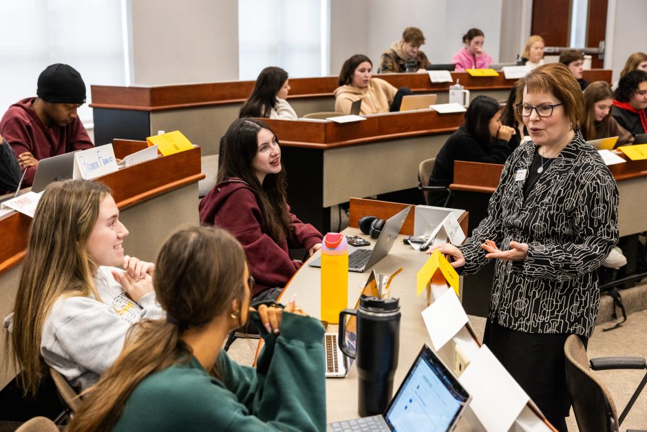 Students seated in a classroom speaking to a professor