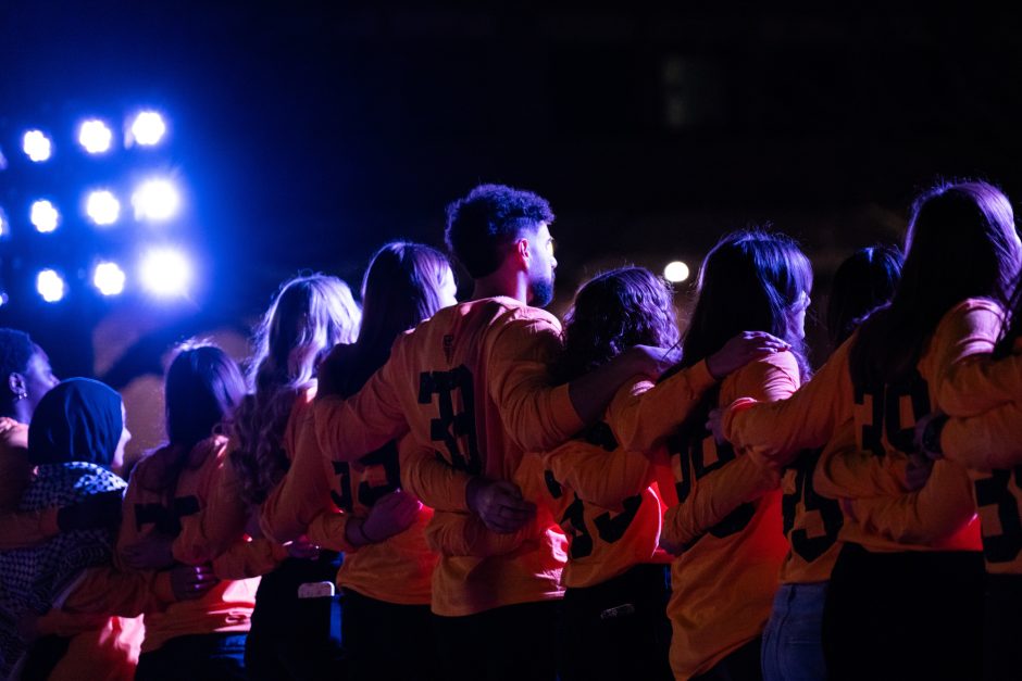Backs of students standing in a line with arms around each others' backs