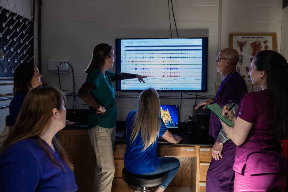 People gathered around large screen that displays data