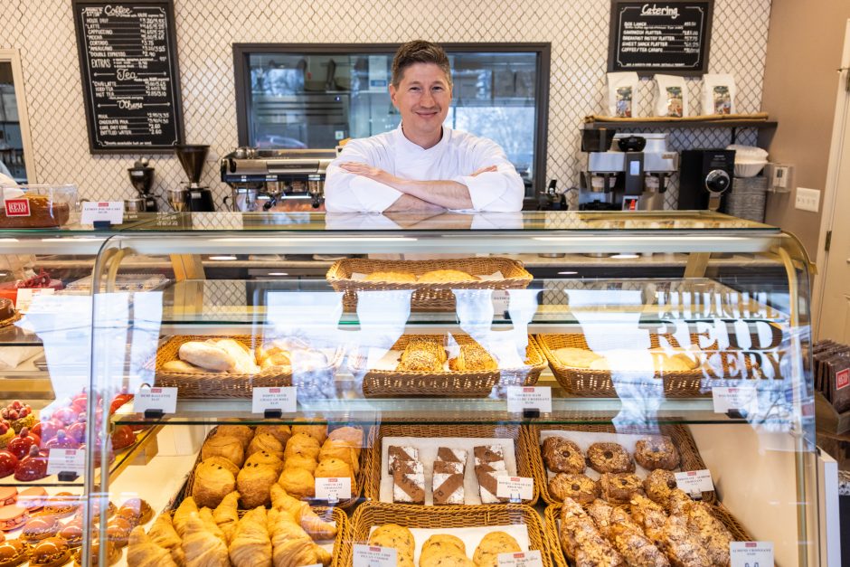 Baker standing behind case of baked goods