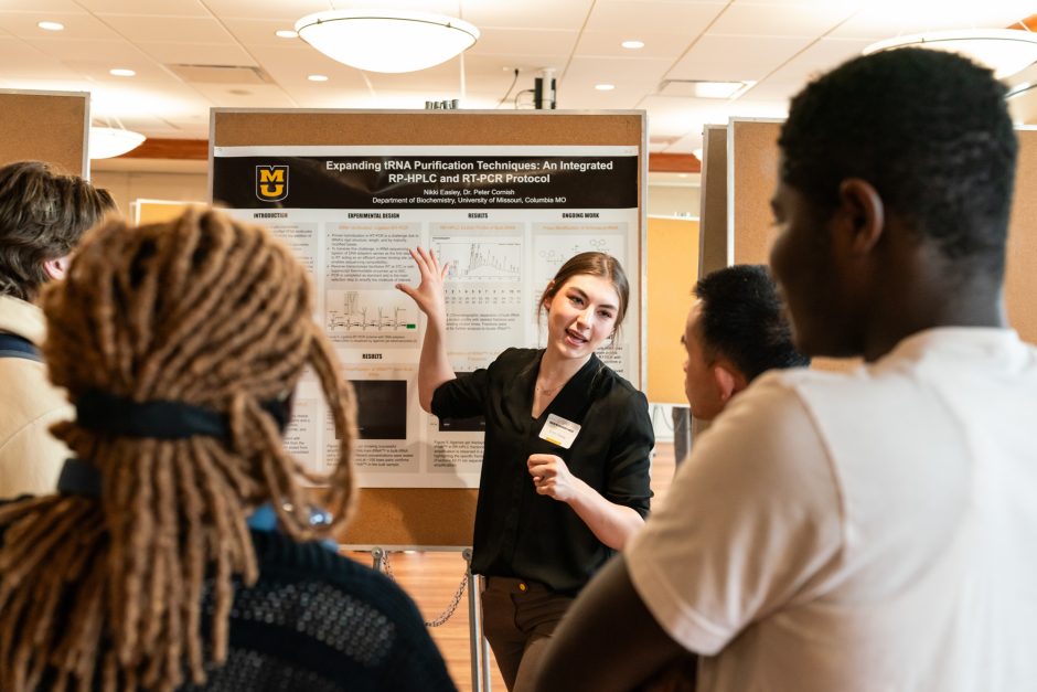 Student explaining research poster to a group of people