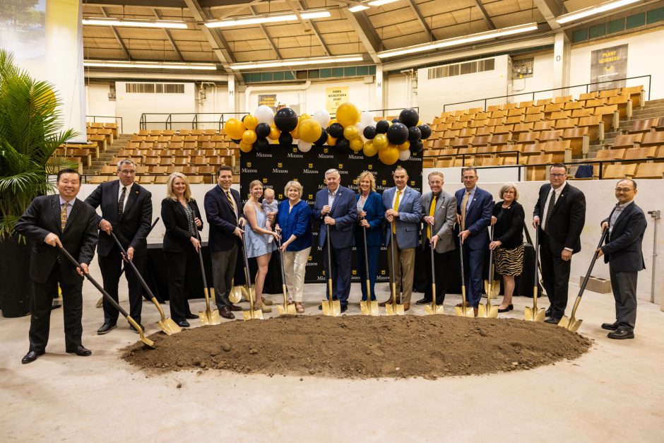 Group of people holding shovels at building groundbreaking ceremony