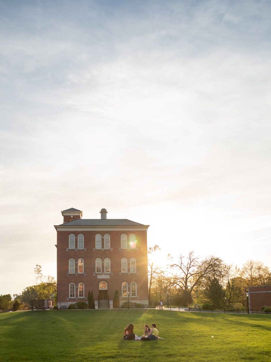 Three students sitting on the ground outside