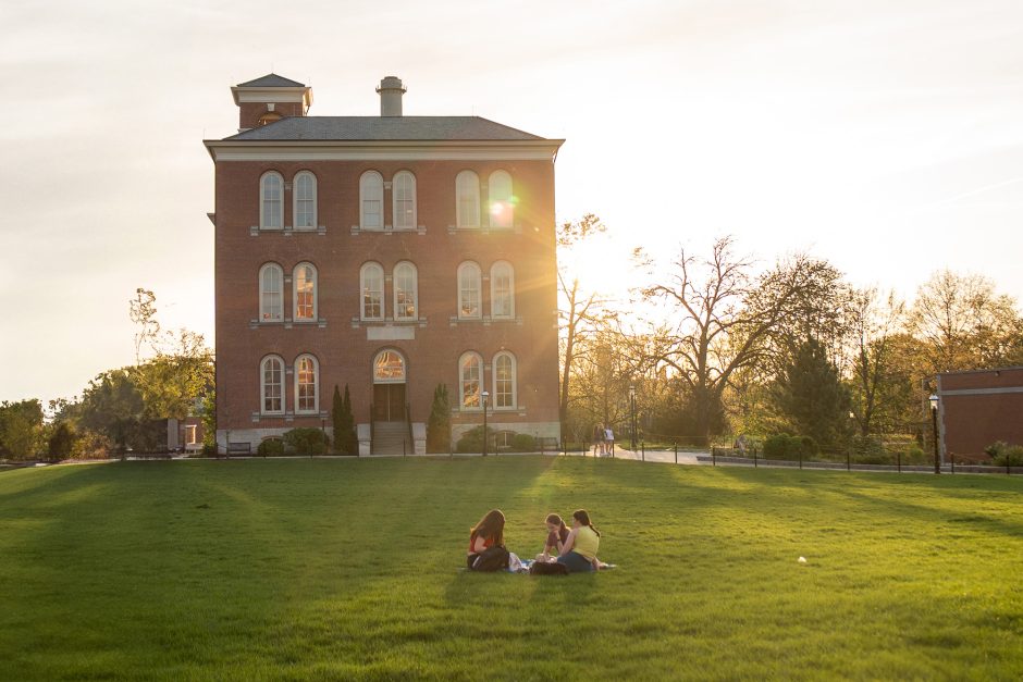 Students have a picnic on the Quad. A red brick building is in the background.