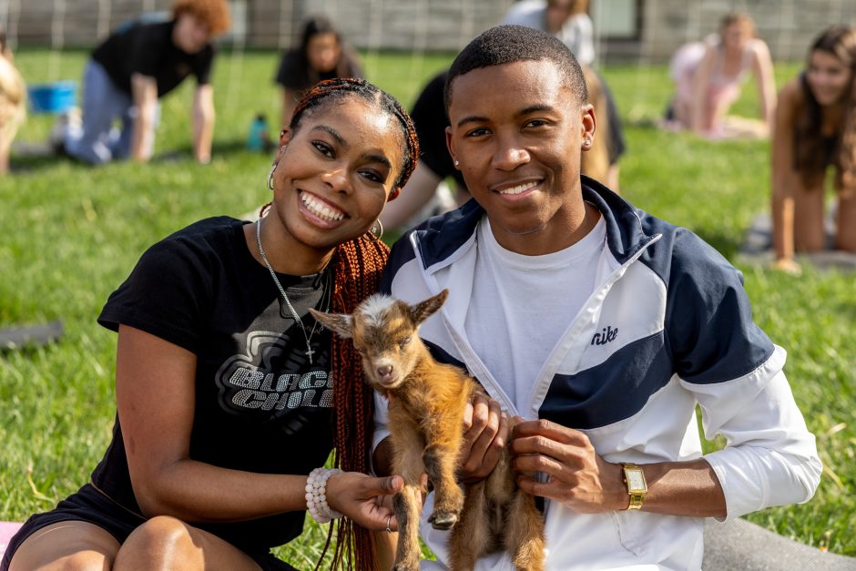 Two students holding a young goat
