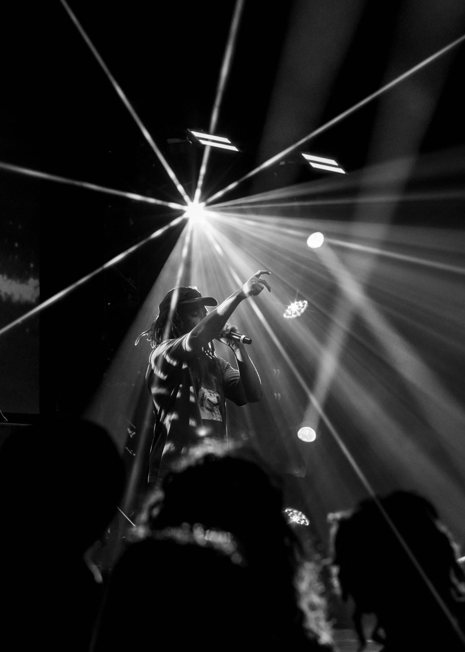 Person on stage with arm raised and microphone in hand