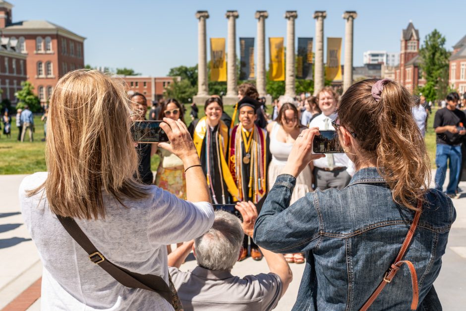 Family members taking photos of graduates in front of the Columns