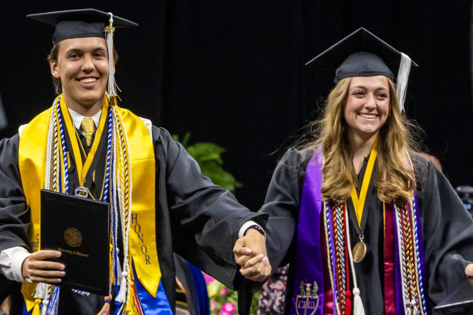 Two graduates holding hands during ceremony