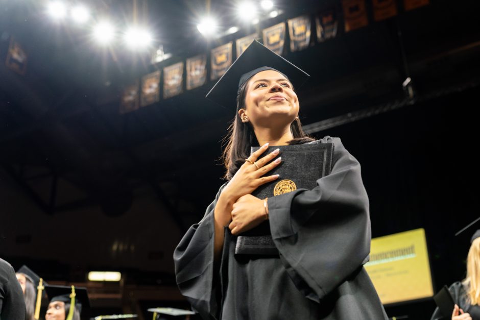 Student holding diploma to chest
