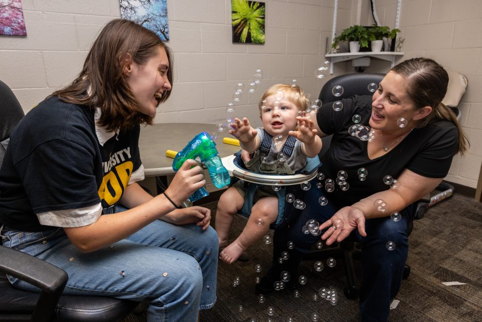 Students working with small child and blowing bubbles