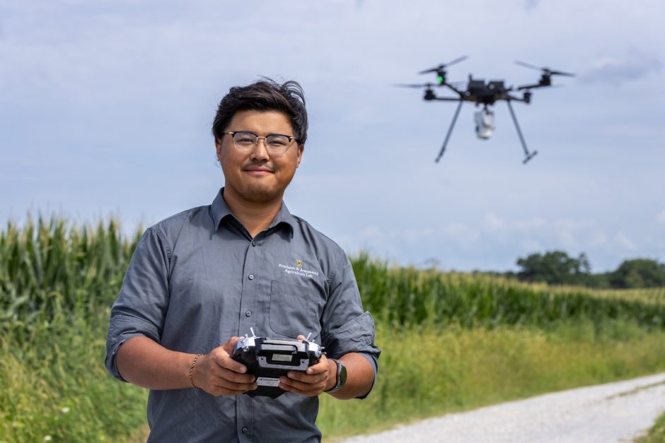 Researcher holding controls as drone hovers nearby