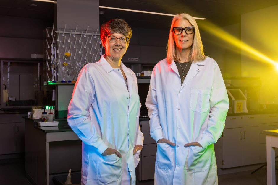 Two researchers in lab coats with their hands in their pockets