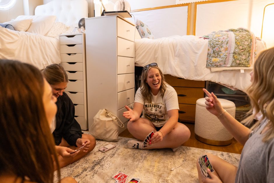 Students laughing while sitting on the floor of a dorm room