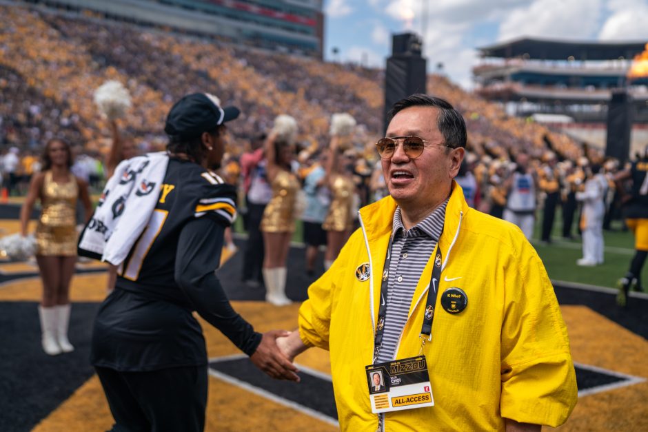 University president shaking hands with a football player