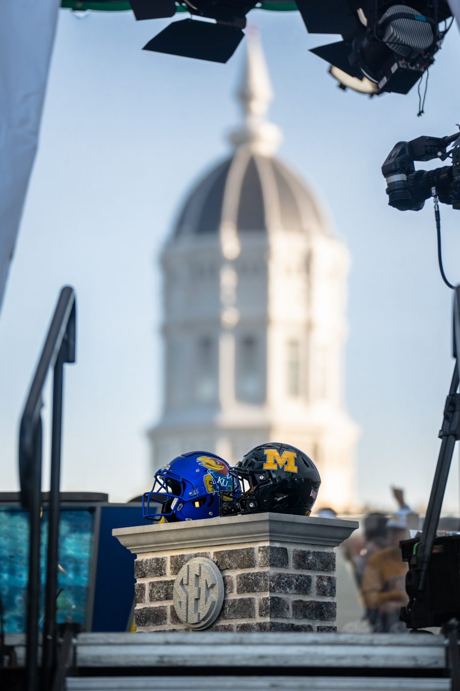 Mizzou and Kansas football helmets with Jesse Hall in the background