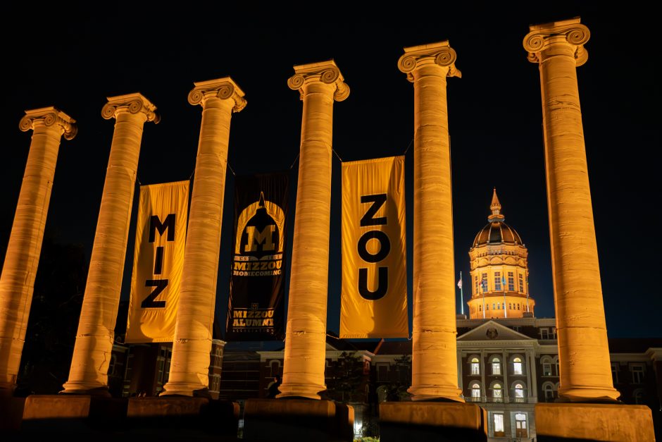 The Columns with banners and a lit Jesse Hall dome in the background