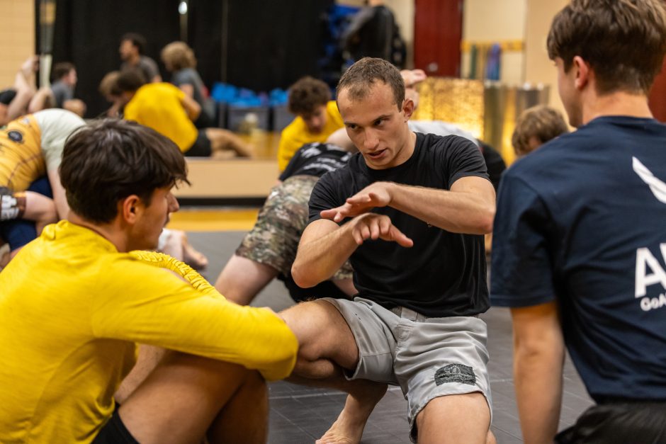 Student kneeling and talking to another student in martial arts gym