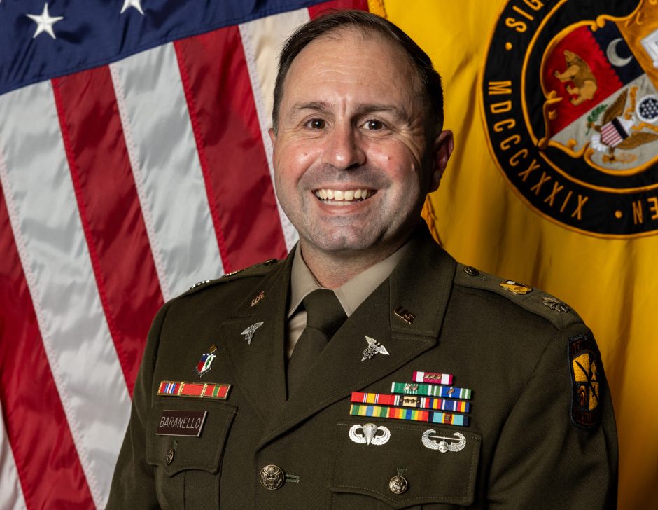 Person in military uniform in front of an American flag