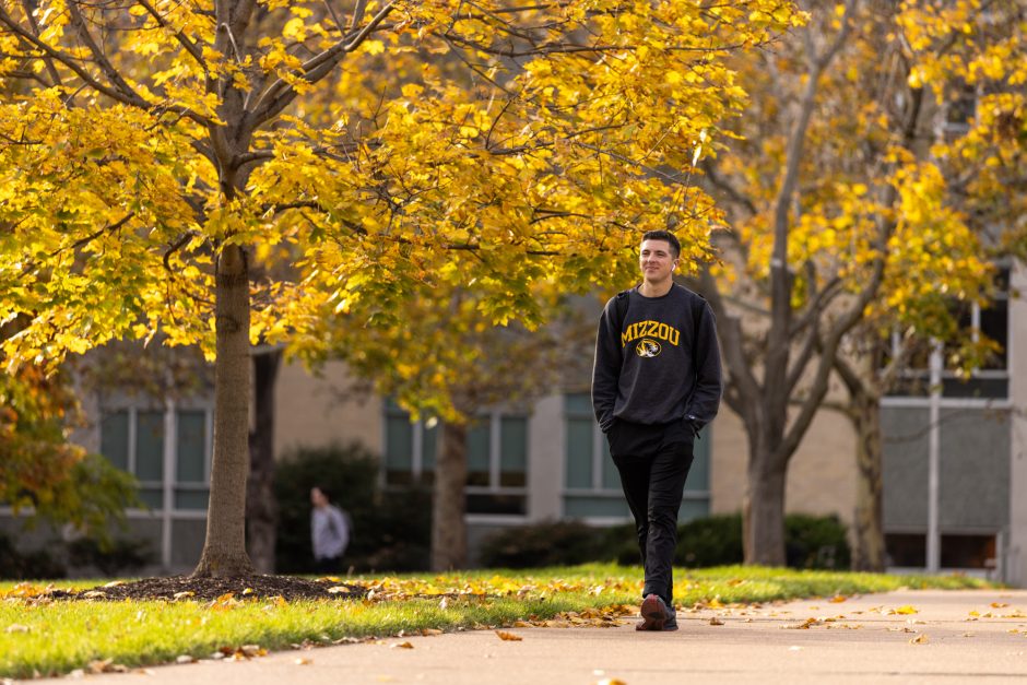 Student walking outside with hands in pockets