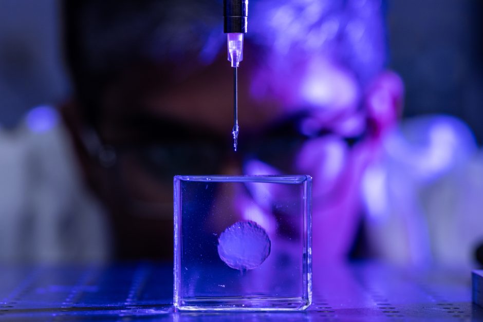 A small 3D-printed brain and a researcher looking on in the background