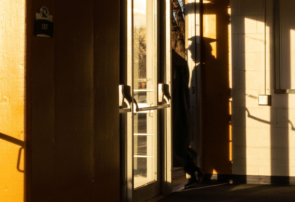 Silhouette of graduate walking out of a door