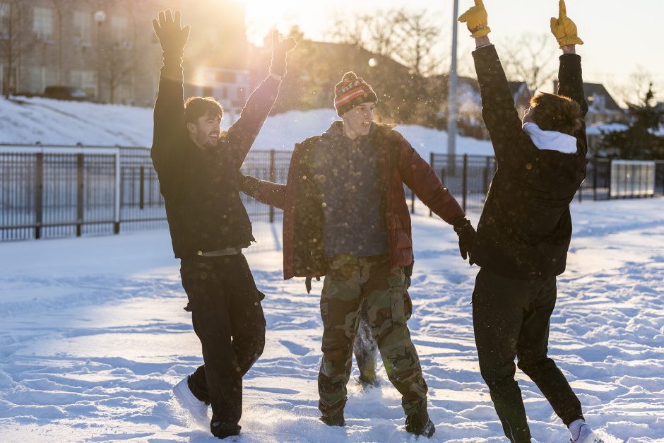 Three students playing outside in the snow