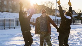 Three students playing outside in the snow