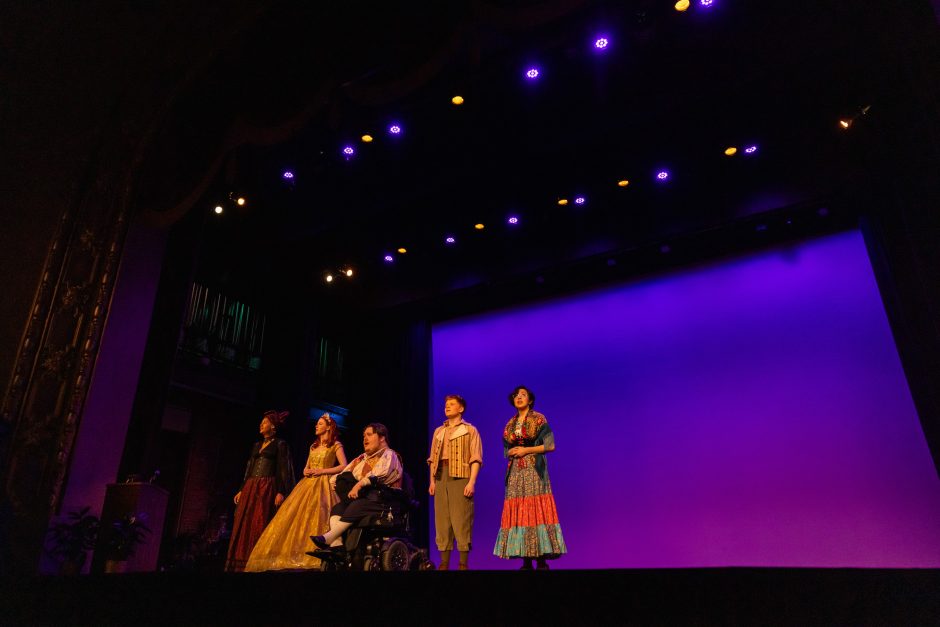 Five cast members of a show lined up on stage