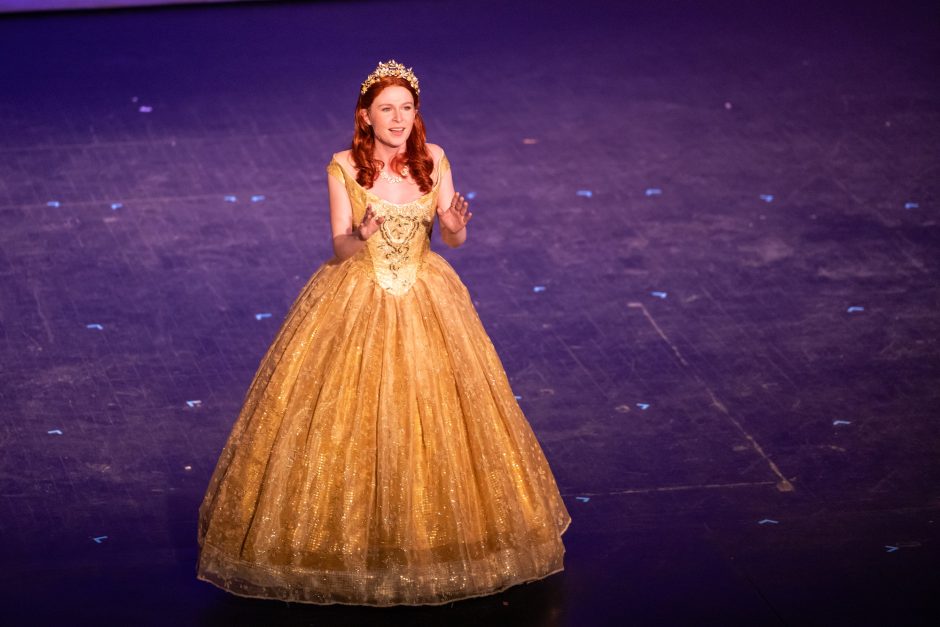 A student in a formal gown performing on stage