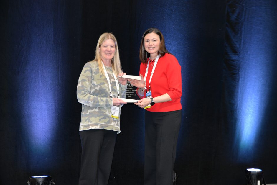 Two people on a stage holding an award