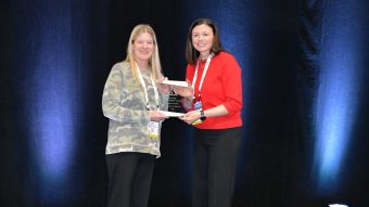 Two people on a stage holding an award