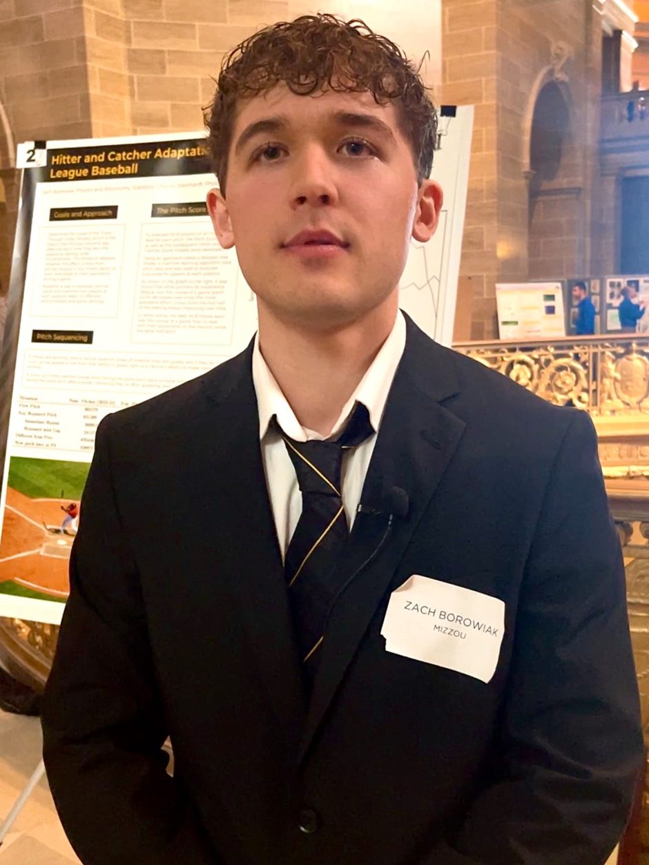 Student standing in front of research poster