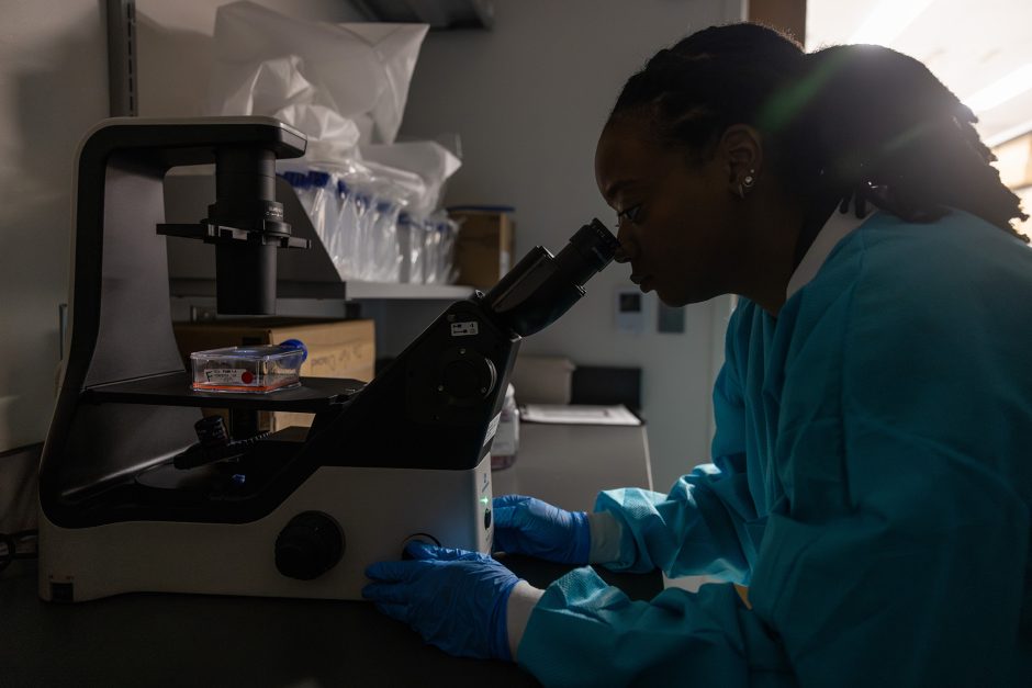 Student researcher looking into a microscope