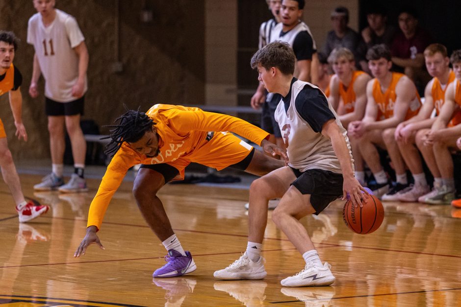 Student dribbling basketball behind back to avoid defender